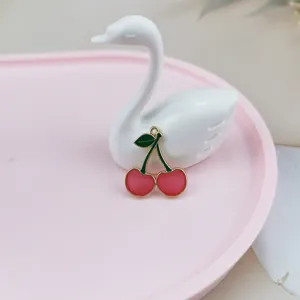 Close-up detail shot of a cute red cherry enamel metal charm pendant for DIY jewelry making.