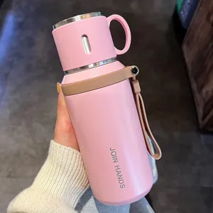 Vista detallada de termo de acero inoxidable rosa, taza portátil con separación y correa.