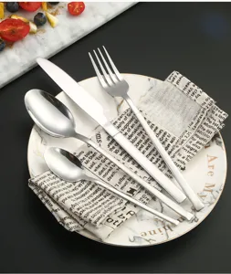 Stainless steel cutlery set detail showing knife, fork, and spoons on elegant plate.