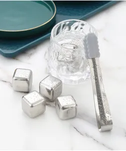 Detailed shot of stainless steel ice cubes set featuring metal cubes, glass cup and tongs.