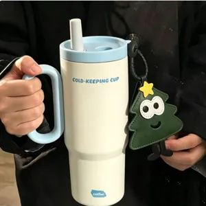 Detail shot of stainless steel insulated tumbler with handle, straw and cute tree pendant.