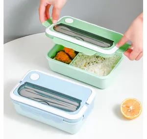 Compartment bento lunch box detail showing tableware set and food display on clean table.