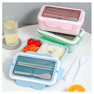 Fiambrera bento portátil de múltiples compartimentos en detalle con cubiertos y comida.