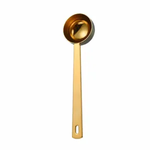 Stainless steel measuring spoon detail, gold finish, long handle design, baking tool.
