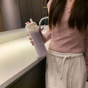 Detailansicht einer lila Trinkflasche aus Kunststoff mit Strohhalmdeckel in der Küche.