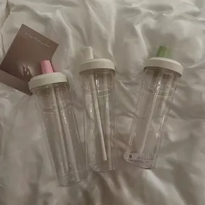 Transparent straw water cup detail showing clear body, white lid and colorful plugs.