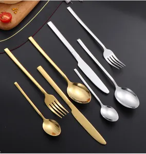 Detalle de juego de cubiertos de acero inoxidable con cuchillos, tenedores y cucharas dorados.
