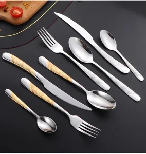 Stainless steel cutlery set detail, silver and gold textured handle knife fork spoon.