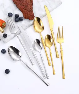 Detailed view of stainless steel cutlery set, including steak knife, fork, and spoon in silver and gold.