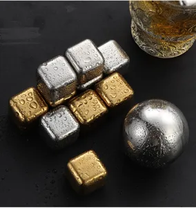 Nahaufnahme von Edelstahl Whisky Eiswürfeln und Metallkugel auf nasser Oberfläche.