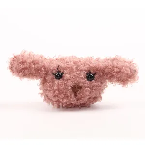 Detailopname van de pluizige roze puppy pluche charm met krullend bont en schattig gezicht.