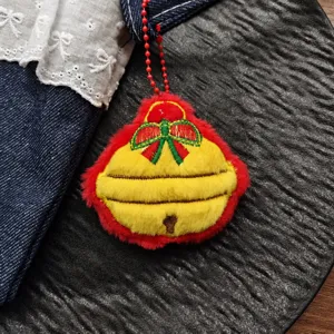 Close-up detail shot of a cute Christmas bell plush pendant with red bow and hanging chain.
