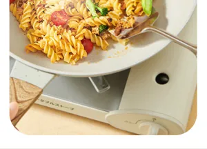 Kitchen non-stick frying pan with portable stove cooking delicious pasta in warm light view