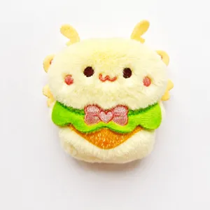 Cute plush bee brooch detail shot, soft yellow furry texture with green collar and bow.
