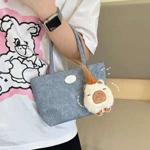 Blue denim tote bag with cute capybara plush pendant, stylish daily accessory for women.