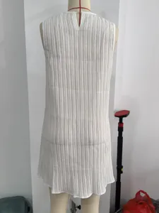 White sleeveless pleated mini dress featuring a classic round neckline and vertical texture.