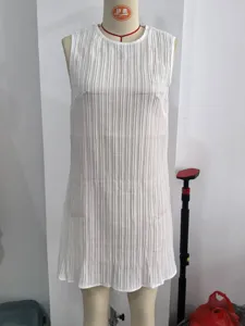 Detailed view of white sleeveless pleated dress, featuring a classic round neckline and texture.