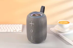 Gros plan d'un haut-parleur Bluetooth portable en tissu gris avec anneau LED sur le bureau.