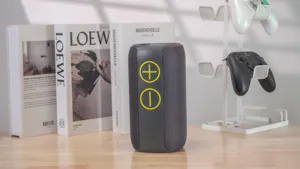 Portable wireless bluetooth speaker with fabric mesh and large control buttons for outdoor use.