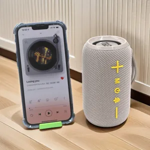 Portable waterproof wireless Bluetooth speaker with fabric mesh and tactile buttons, detailed view.