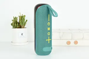 Vue détaillée de l'enceinte Bluetooth sans fil portable avec maille en tissu cyan et sangle.