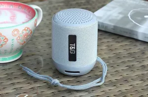 Altoparlante bluetooth portatile grigio wireless con cordino intrecciato su tavolo in rattan dettaglio
