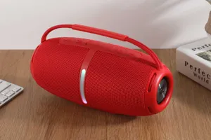Close-up of a vibrant red portable wireless Bluetooth speaker with carrying strap on desk.