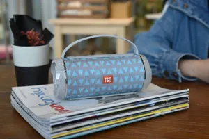 Detailansicht des tragbaren kabellosen Bluetooth-Lautsprechers mit Griff und blauem Stoffnetz.