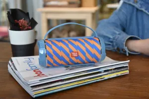 Tragbarer kabelloser Bluetooth-Lautsprecher mit blau-orangen Streifen und praktischem Tragegriff.