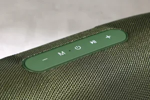 Outdoor portable waterproof bluetooth speaker with fabric mesh and control buttons detail.