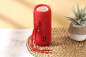 Red fabric wireless Bluetooth speaker detail view, portable waterproof design with strap.