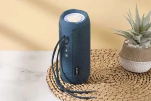 Close-up of portable blue bluetooth speaker with fabric mesh design and handy carrying strap.