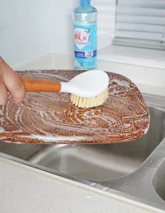 Detailansicht der praktischen Küchenreinigungsbürste mit Holzgriff beim Reinigen des Bretts.