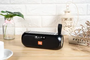 Portable solar bluetooth speaker detail view with control buttons and hanging strap in studio.