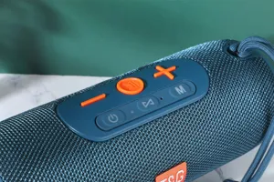 Gros plan detaille de l'enceinte Bluetooth cylindrique portable avec tissu bleu et boutons.