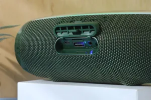 Détail de haut-parleur Bluetooth portable vert montrant le tissu maille et le volet