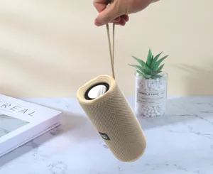Tragbarer kabelloser Bluetooth-Lautsprecher in Khaki mit Trageband, Nahaufnahme.