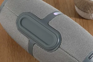 Close up detail of portable wireless bluetooth speaker with gray fabric mesh and rubber accents.