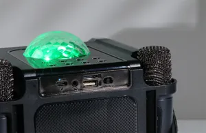 Close-up detail of wireless Bluetooth karaoke speaker with colorful disco ball and mic slots.