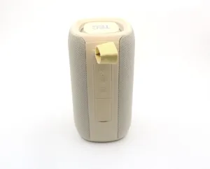 Portable bluetooth speaker detail view showing beige fabric mesh and control buttons.