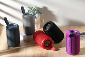 Detailaufnahme tragbarer Bluetooth-Lautsprecher in bunten Farben mit Stoffbezug und Schlaufe.