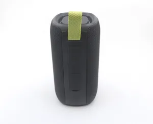 Close-up detail of portable wireless bluetooth speaker with black mesh fabric and green strap.