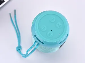 Portable cyan Bluetooth speaker with lanyard, wireless audio device with top control buttons.