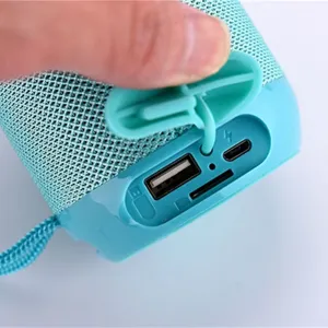 Portable bluetooth speaker with mesh fabric design, showing USB and TF card slot ports.