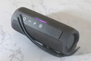 Portable bluetooth speaker detail shot, cylindrical mesh fabric design with convenient lanyard.