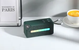 Nahaufnahme des tragbaren gruenen Bluetooth Lautsprechers mit RGB Lichtleiste auf dem Tisch.