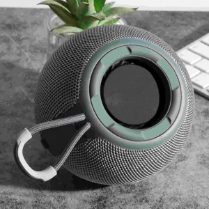 Portable spherical Bluetooth speaker in gray mesh fabric with hanging strap for outdoor use.
