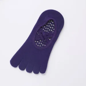 Detail view of purple five toe non slip grip yoga socks with cross straps and dots.