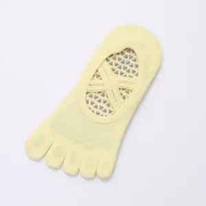 Yellow five-toe yoga socks with cross straps and anti-slip silicone dots for pilates.