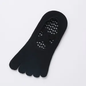 Close-up detail of black five-toe yoga socks with anti-slip grip and crisscross straps.